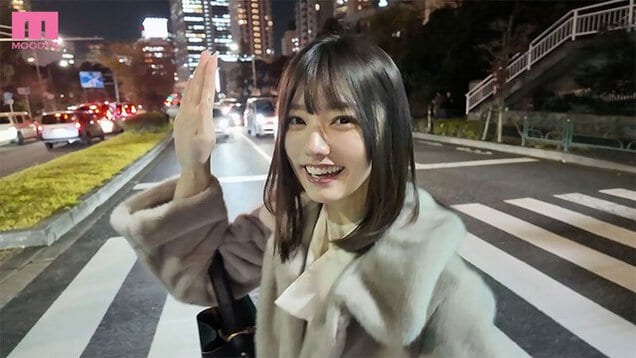 夜の道路でコート姿の宮下玲奈が片手を上げて笑う